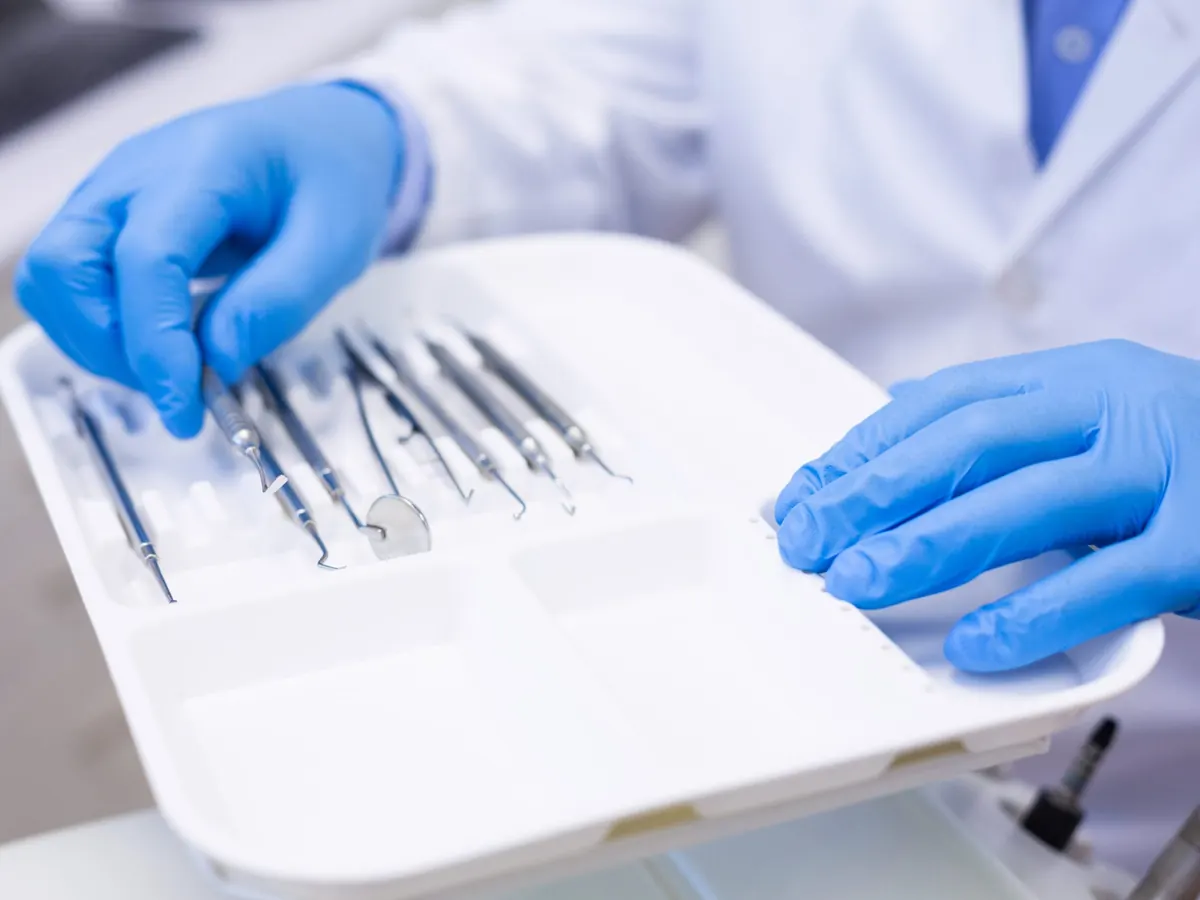 Medic pregatind instrumentarul stomatologic steril pe o tava