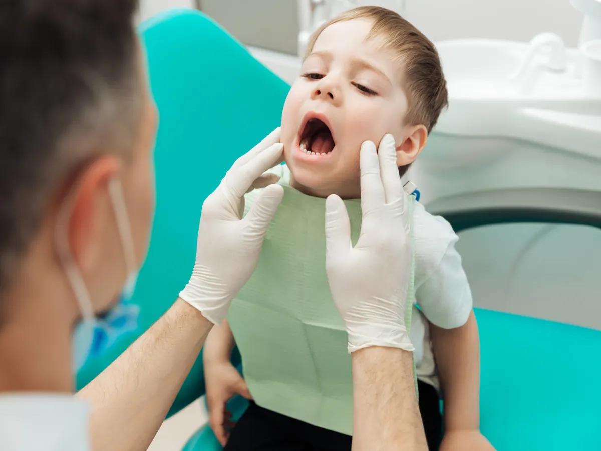 Medic stomatolog examinand dintii unui baietel