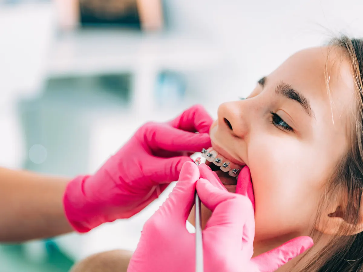 Medic ortodont verificand aparatul dentar al unei adolescente